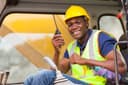 Site worker in a hard hat and high-visibility vest using a two-way radio in a cab